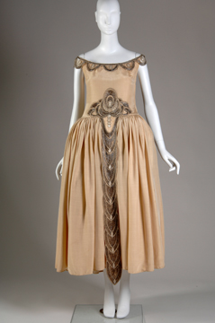 mannequin in a beige dress with scoop neckline and full skirt with dropped waist