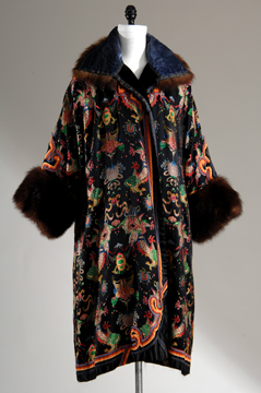 mannequin in a black opera coat with fur cuffs and colars and decorated with colorful embroidery