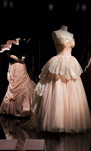platform view of (left) Charles James
Tree dress with strapless, chevron pleated long torso bodice and petal stole in black velvet lined in pink satin with pink satin full length gloves and (right) Christian Dior “Venus” evening dress with sequins, rhinestones, crystal, and net.