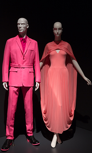 (L) neon pink pantsut with detachable belt. (R) pink silk jersey sleeveless dress with an extended long train vertical gathering at center back which allows the train to be flipped over the head to form a self-draped cape.